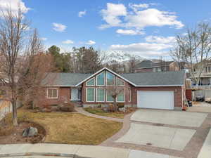 View of front facade with a garage, a mountain view, and a front lawn