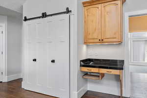 Kitchen with dark wood-type flooring, a barn door, a textured ceiling, and light brown cabinets