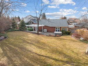 Back of property featuring a yard, a patio, and a pergola