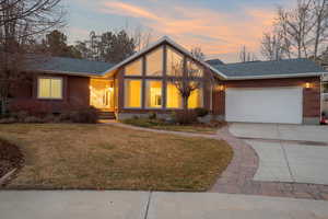 View of front of home with a garage and a lawn