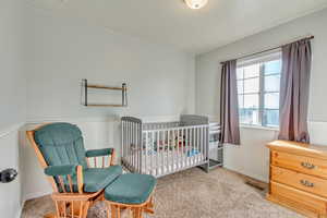 Bedroom with a nursery area and light carpet