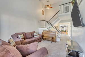 Carpeted living room featuring a high ceiling and ceiling fan