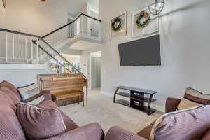 Living room featuring a towering ceiling and light carpet