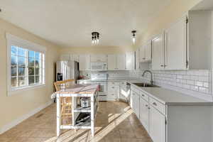 Kitchen featuring a center island, stainless steel appliances, white cabinetry, and light tile patterned floors