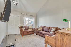 Living room with high vaulted ceiling and light carpet