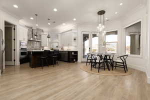 Dining room with light hardwood / wood-style flooring, crown molding, and a notable chandelier