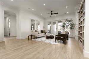 Living room featuring ornamental molding, light wood-type flooring, ceiling fan, and french doors