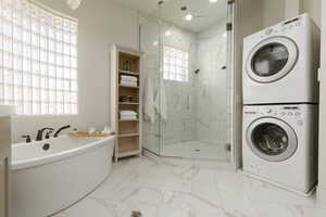 Bathroom featuring stacked washing maching and dryer and plus walk in shower