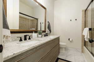 Full bathroom featuring enclosed tub / shower combo, vanity, and toilet