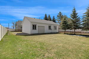 Rear view of property with fence, a yard, and a garage