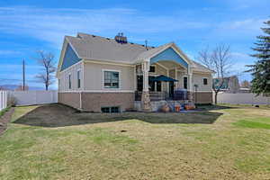 Rear view of house with a lawn, a fenced backyard, a gate, and brick siding
