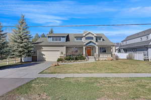 View of front of property with fence, a front lawn, driveway, brick siding, and roof with shingles
