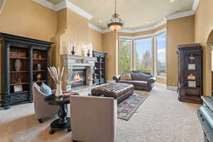 Carpeted living room with a high end fireplace and ornamental molding