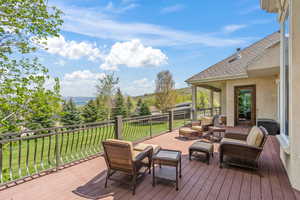 Wooden terrace featuring a mountain view, outdoor lounge area, and a lawn