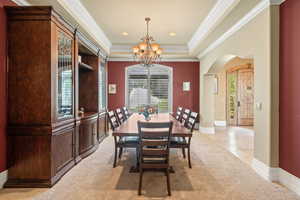 Carpeted dining area featuring crown molding, a chandelier, and a raised ceiling