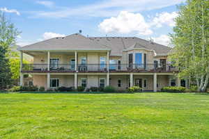 Back of house featuring a balcony and a yard