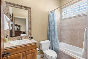 Full bathroom featuring vanity, toilet, and shower / bathtub combination with curtain