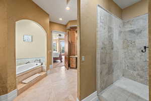 Bathroom featuring tiled bath, tile patterned floors, and ceiling fan