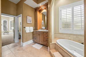 Bathroom with tile patterned flooring, tiled bath, a wealth of natural light, and vanity