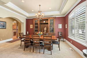 Dining area featuring crown molding, light colored carpet, and a raised ceiling