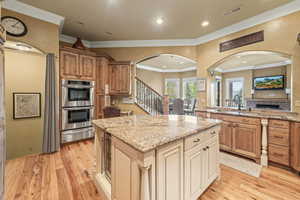 Kitchen featuring light wood-type flooring, a center island, light stone counters, and stainless steel double oven