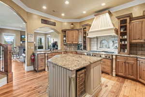 Kitchen with premium range hood, light hardwood / wood-style floors, a center island, and stainless steel gas cooktop