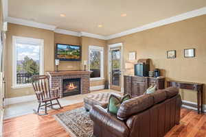 Living room featuring light hardwood / wood-style floors, a brick fireplace, and crown molding