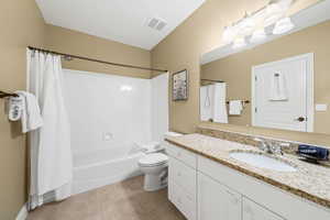 Full bathroom featuring shower / bath combo with shower curtain, toilet, tile patterned floors, and vanity