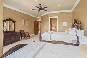 Carpeted bedroom with ceiling fan and crown molding