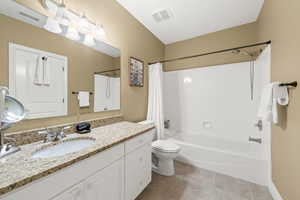 Full bathroom featuring toilet, vanity, shower / bathtub combination with curtain, and tile patterned flooring