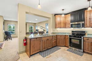 Kitchen featuring light stone countertops, sink, hanging light fixtures, kitchen peninsula, and black electric range