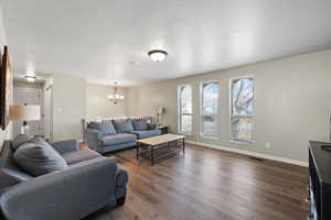 Living room with a chandelier, a textured ceiling, and dark hardwood / wood-style flooring