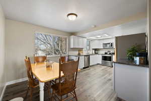 Dining area with sink, light hardwood / wood-style flooring, and a textured ceiling