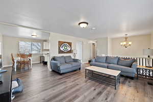 Living room with hardwood / wood-style floors, a textured ceiling, and an inviting chandelier