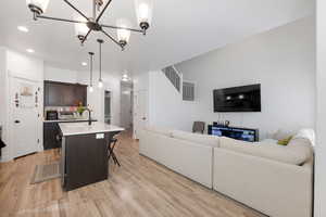 Living room featuring sink, a chandelier, and light hardwood / wood-style flooring