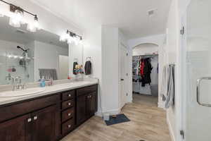 Bathroom featuring a shower with shower door, hardwood / wood-style floors, vanity, and a textured ceiling