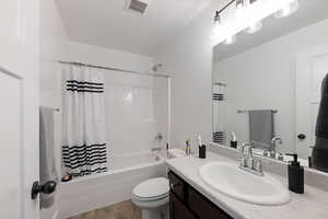 Full bathroom with hardwood / wood-style flooring, toilet, shower / tub combo, and vanity