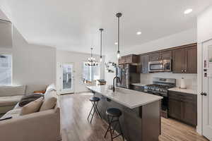 Kitchen with hanging light fixtures, sink, a breakfast bar, an island with sink, and stainless steel appliances