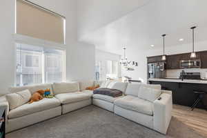 Living room with sink, light wood-type flooring, a notable chandelier, and a wealth of natural light