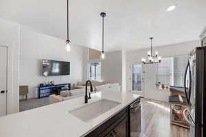 Kitchen with sink, hanging light fixtures, black dishwasher, and stainless steel refrigerator