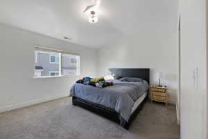 Carpeted bedroom featuring lofted ceiling