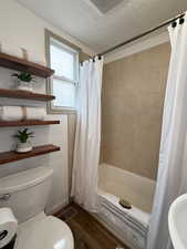 Bathroom with hardwood / wood-style floors, shower / bath combo, and a textured ceiling