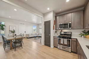 Kitchen featuring gray cabinets, light wood-type flooring, a wealth of natural light, and appliances with stainless steel finishes