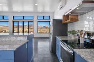 Kitchen featuring a wall mounted air conditioner, decorative backsplash, blue cabinets, ventilation hood, and stainless steel electric stove