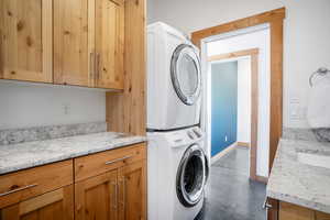 Clothes washing area with cabinets, stacked washer / dryer, and sink