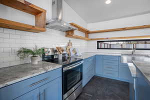 Kitchen with sink, blue cabinetry, island exhaust hood, electric range, and decorative backsplash