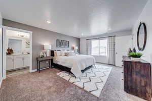 Carpeted bedroom featuring sink and connected bathroom