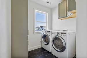 Laundry area featuring dark tile patterned floors, cabinets, and washer and dryer