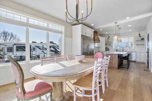 Dining space with sink, light hardwood / wood-style flooring, and a notable chandelier