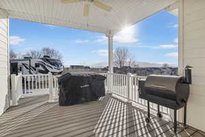 Wooden terrace featuring a mountain view, ceiling fan, and a grill